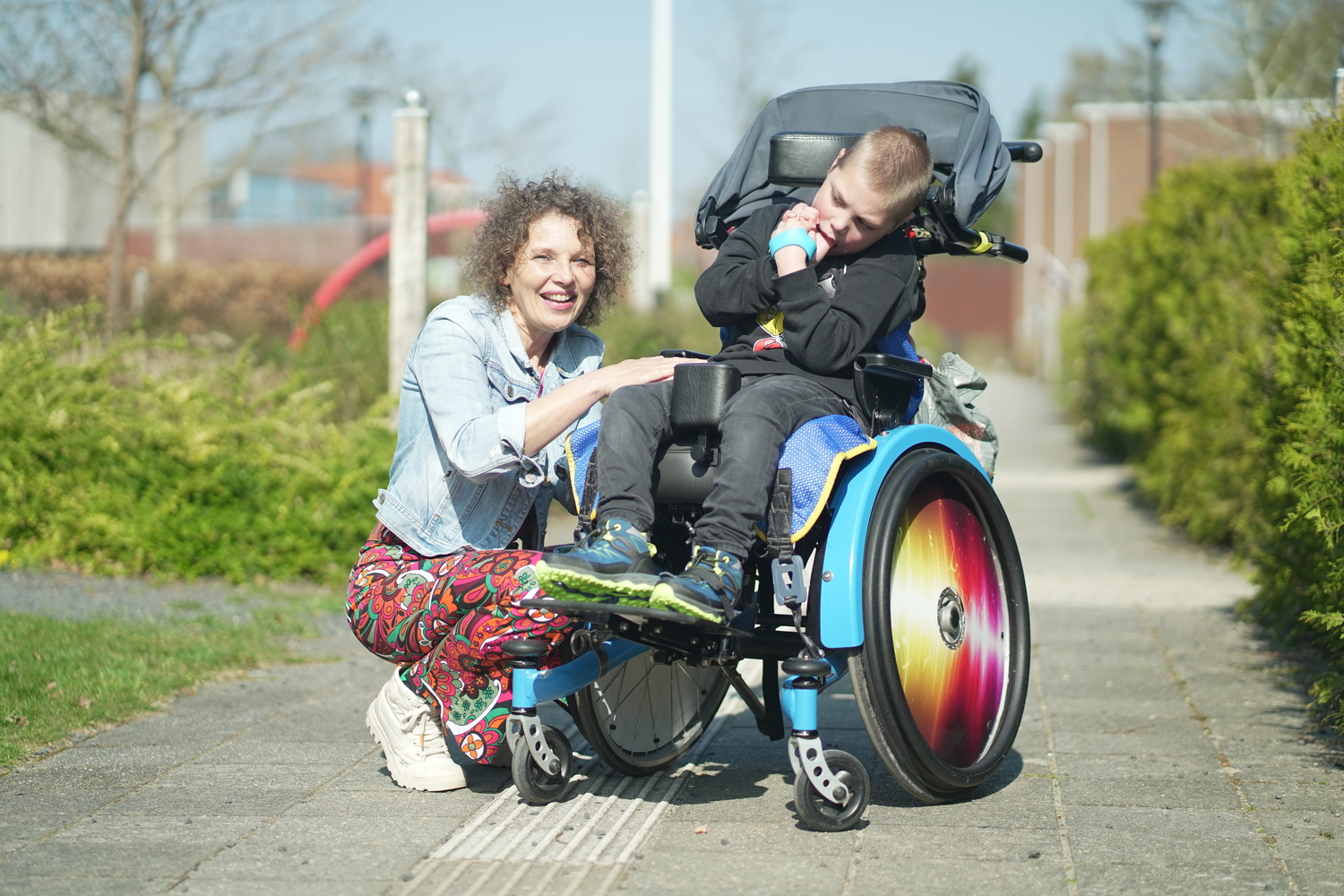 Medewerker en jonge cliënt met een meervoudige beperking in rolstoel poseren samen Medewerker en jonge cliënt met een meervoudige beperking in rolstoel poseren samen
