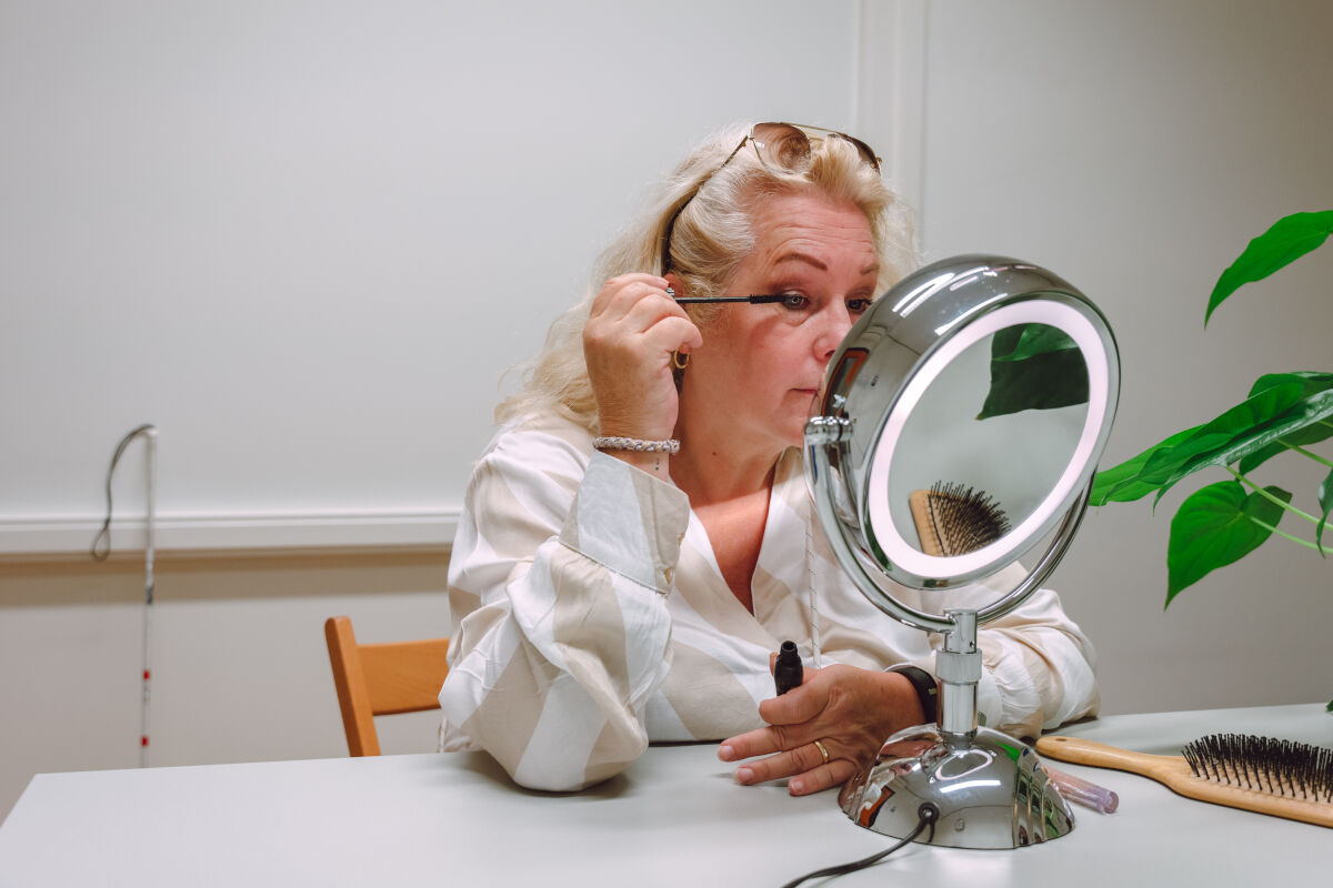 Slechtziende vrouw maakt zichzelf op in de spiegel Slechtziende vrouw maakt zichzelf op in de spiegel