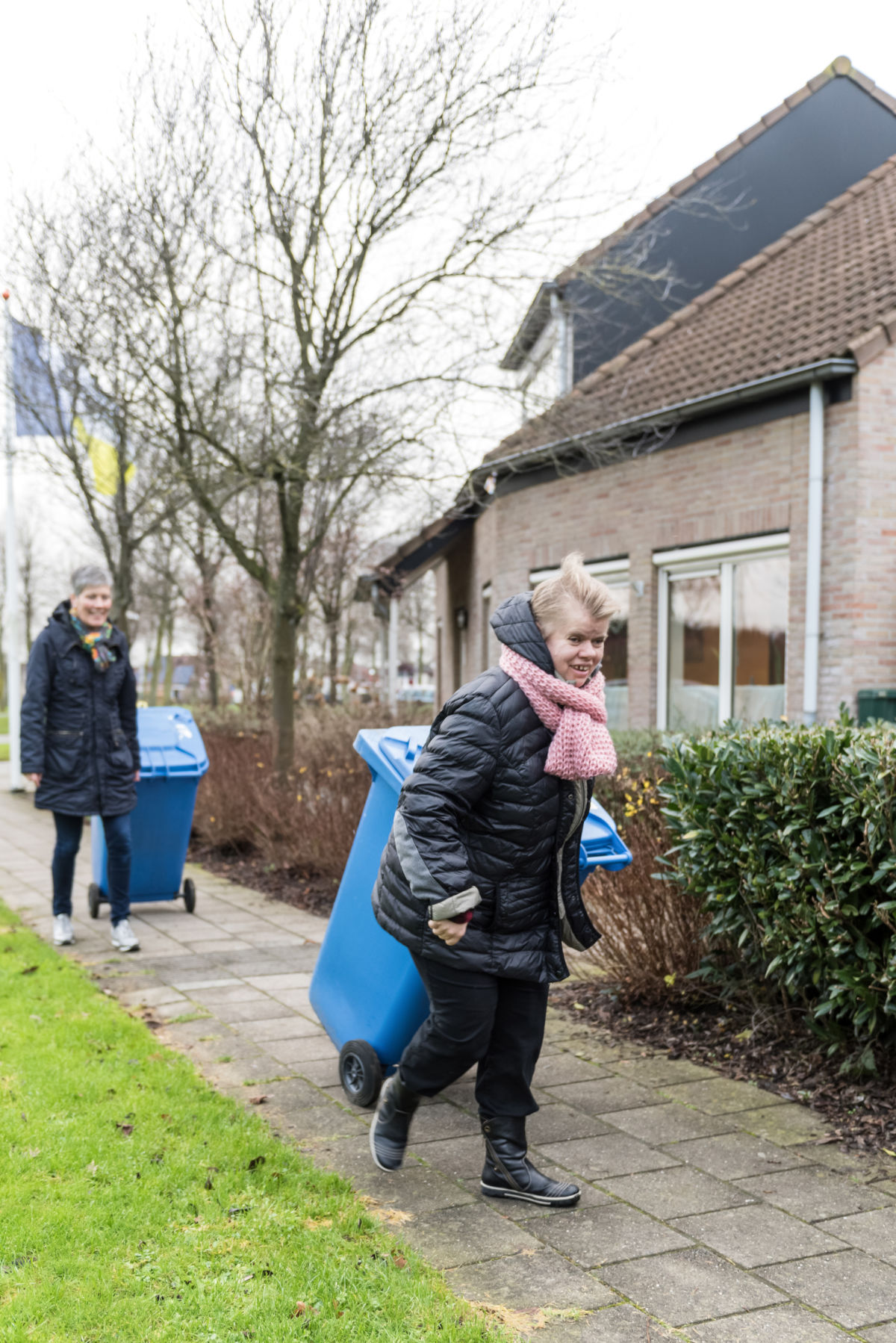 Vrouw zet een blauwe kliko aan de straat bij Visio in Emmen Vrouw zet een blauwe kliko aan de straat bij Visio in Emmen