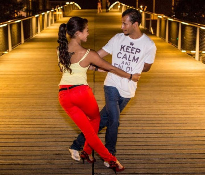 Twee mensen dansen salsa op een verlichte brug