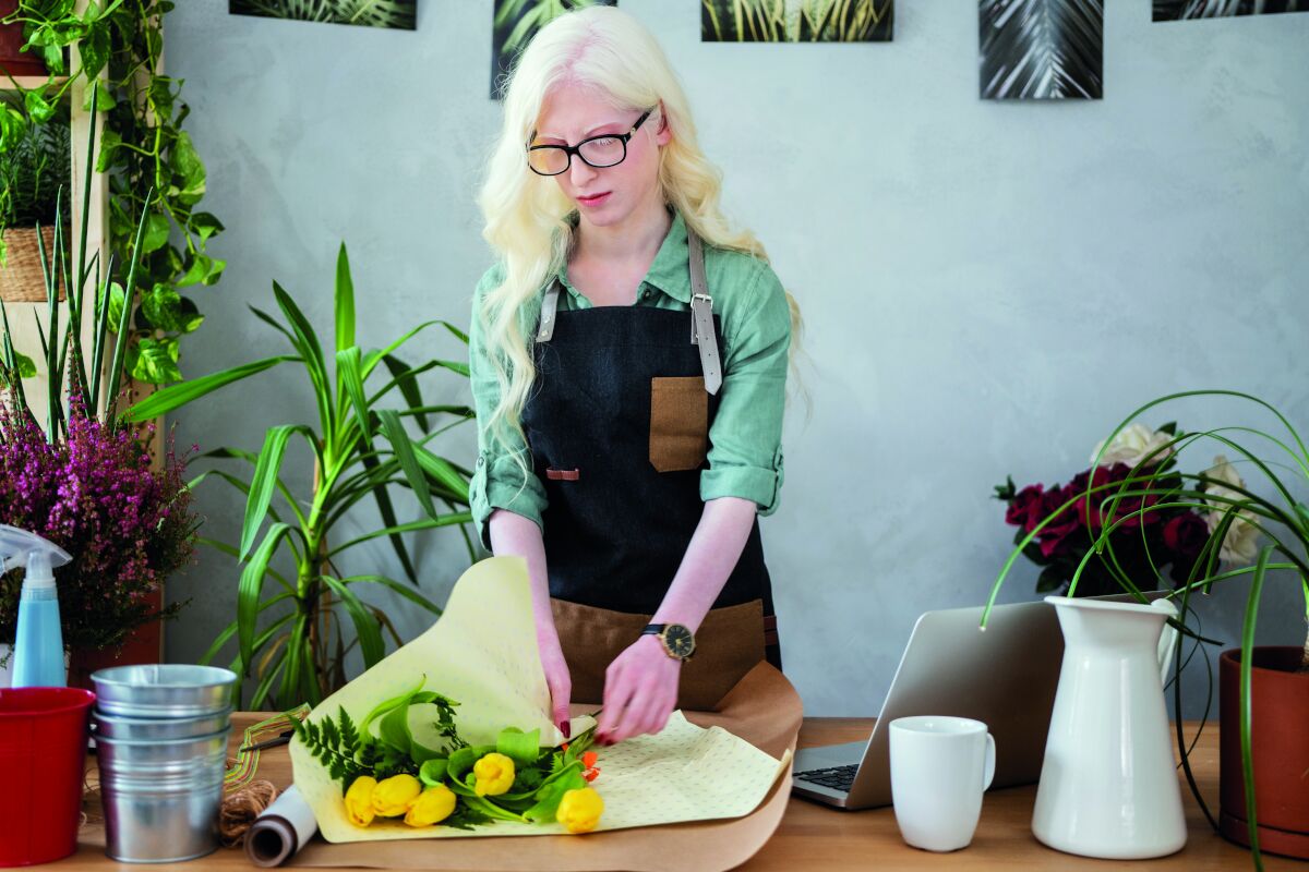 Vrouw met albinisme is aan het bloemschikken Vrouw met albinisme is aan het bloemschikken