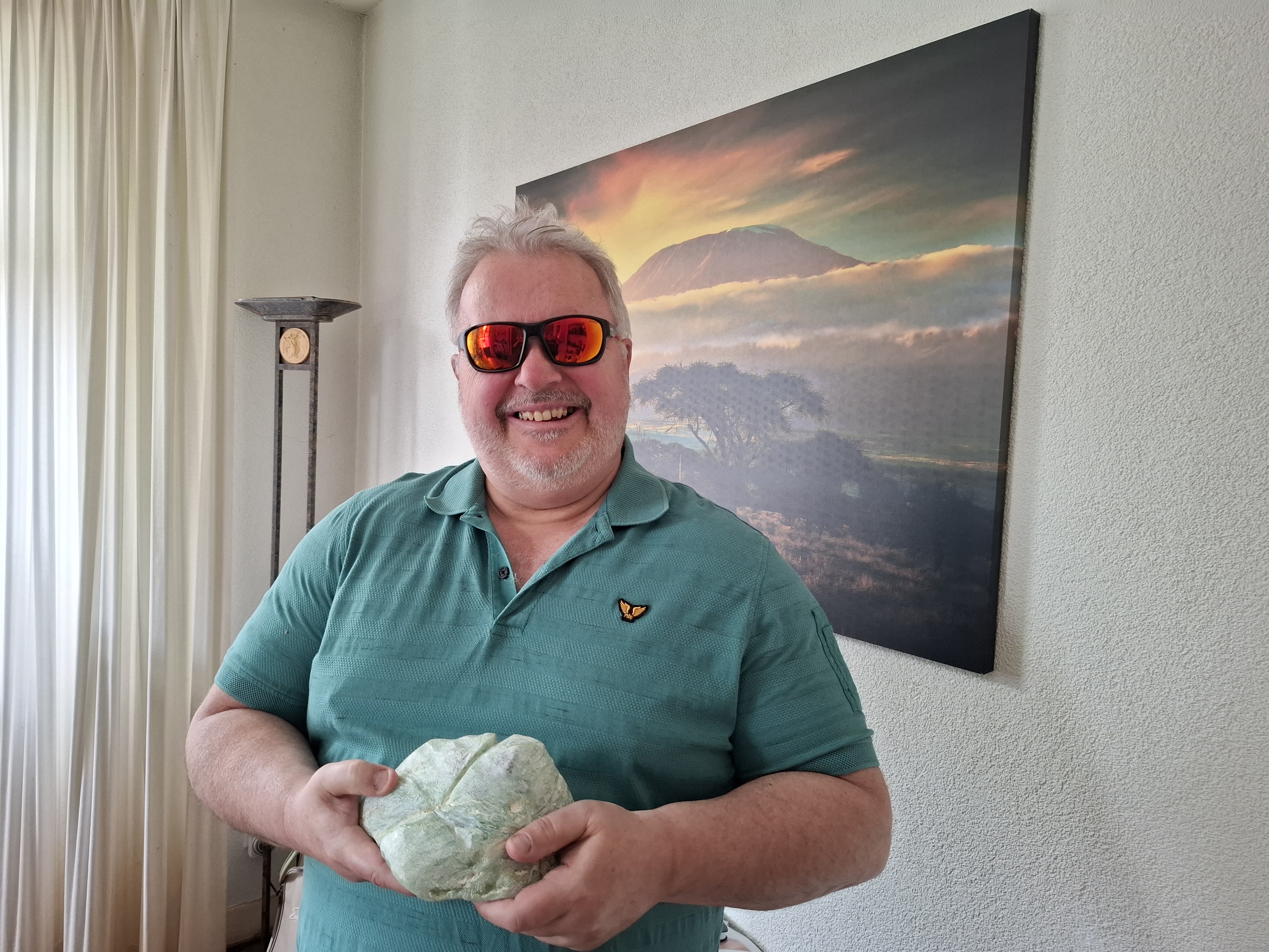 Joska Wolthuis laat zijn speksteen aan de camera zien. Hij draagt een zonnebril en glimlacht naar de camera. Joska Wolthuis laat zijn speksteen aan de camera zien. Hij draagt een zonnebril en glimlacht naar de camera.