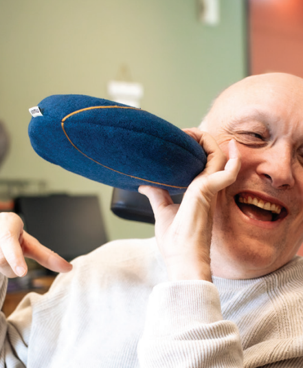 Een cliënt houdt een imnu-kussen tegen zijn gezicht aan. Een cliënt houdt een imnu-kussen tegen zijn gezicht aan.