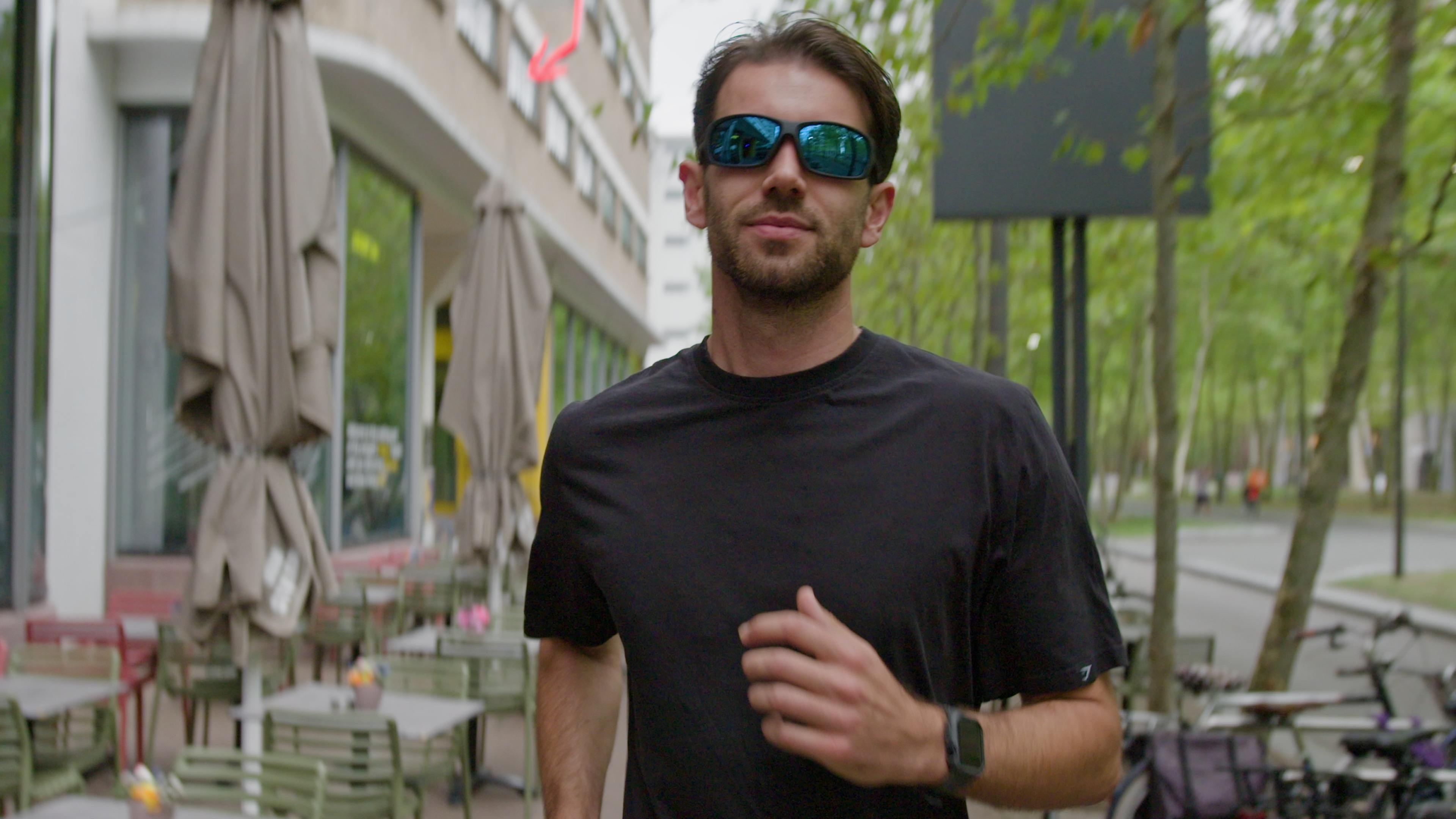 Joost is aan het hardlopen. Hij draagt een zwart sportshirt en een zonnebril. Hij rent richting te camera. Joost is aan het hardlopen. Hij draagt een zwart sportshirt en een zonnebril. Hij rent richting te camera.