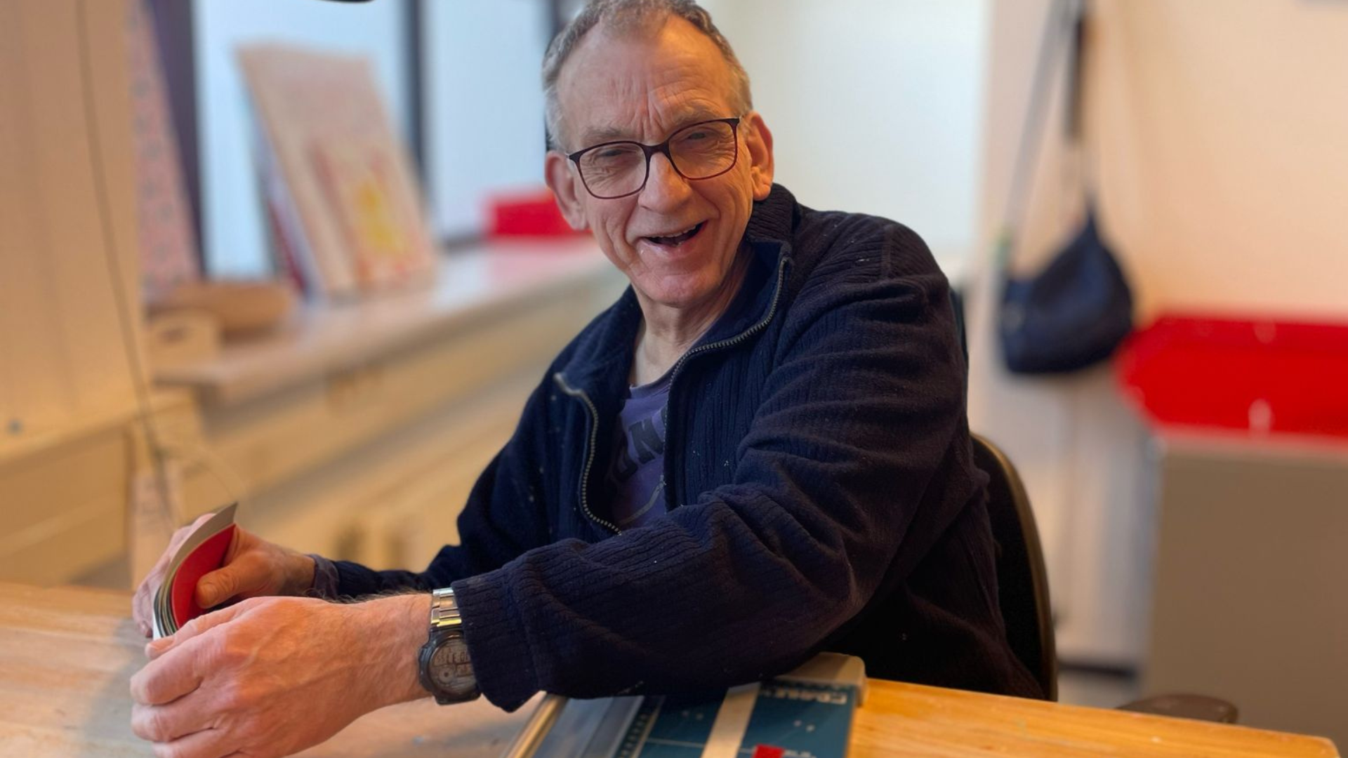 Mannelijke cliënt werkt aan tafel met een papiersnijapparaat Mannelijke cliënt werkt aan tafel met een papiersnijapparaat