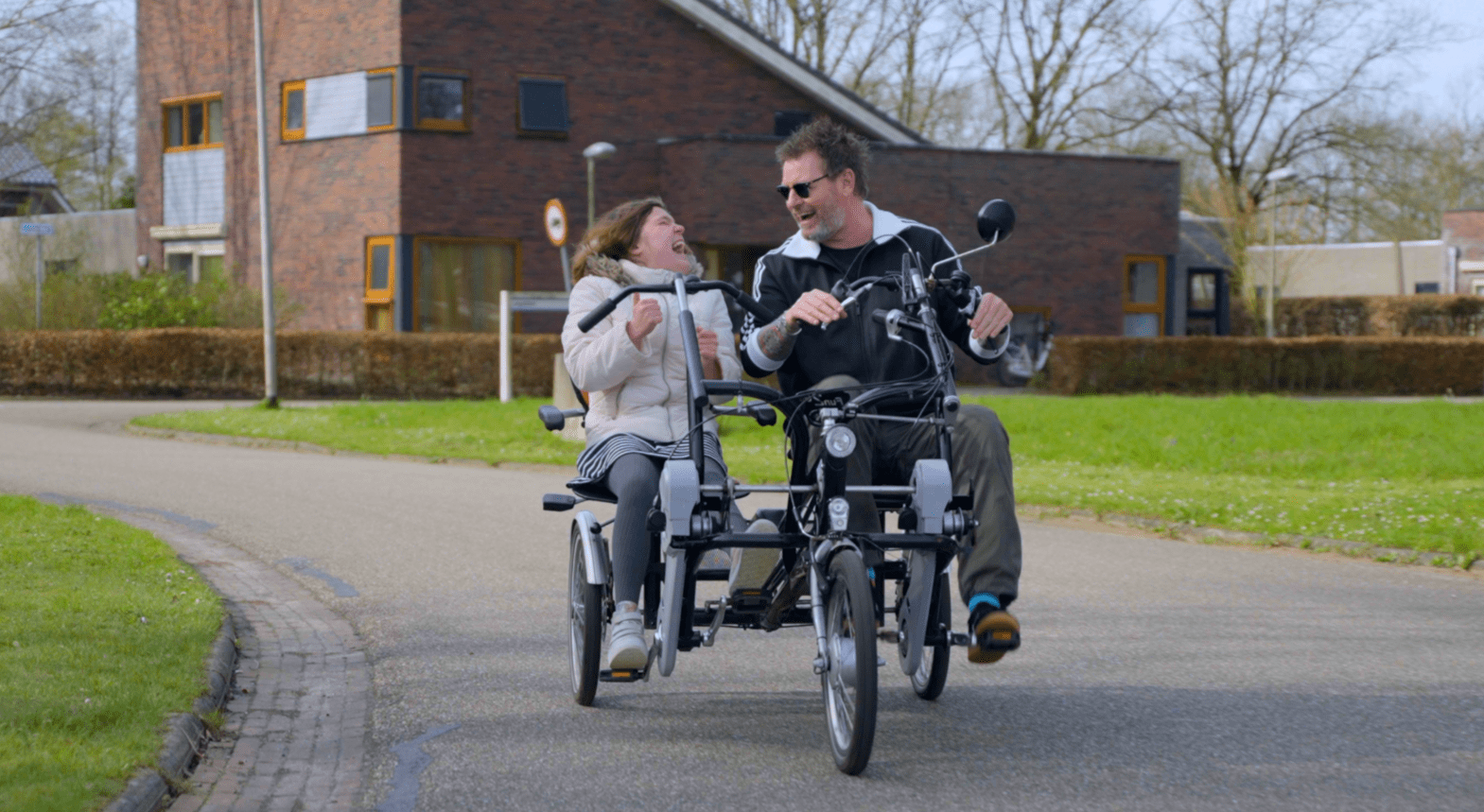 Cliënt met visuele en verstandelijke beperking en begeleider fietsen op de duofiets Cliënt met visuele en verstandelijke beperking en begeleider fietsen op de duofiets