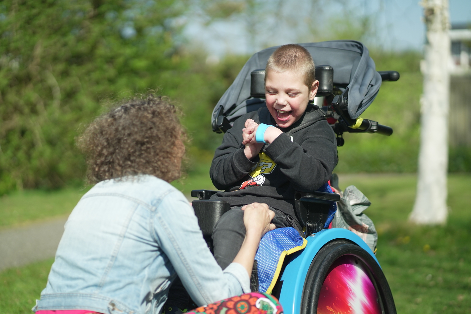Medewerker en jonge cliënt met een meervoudige beperking in rolstoel Medewerker en jonge cliënt met een meervoudige beperking in rolstoel