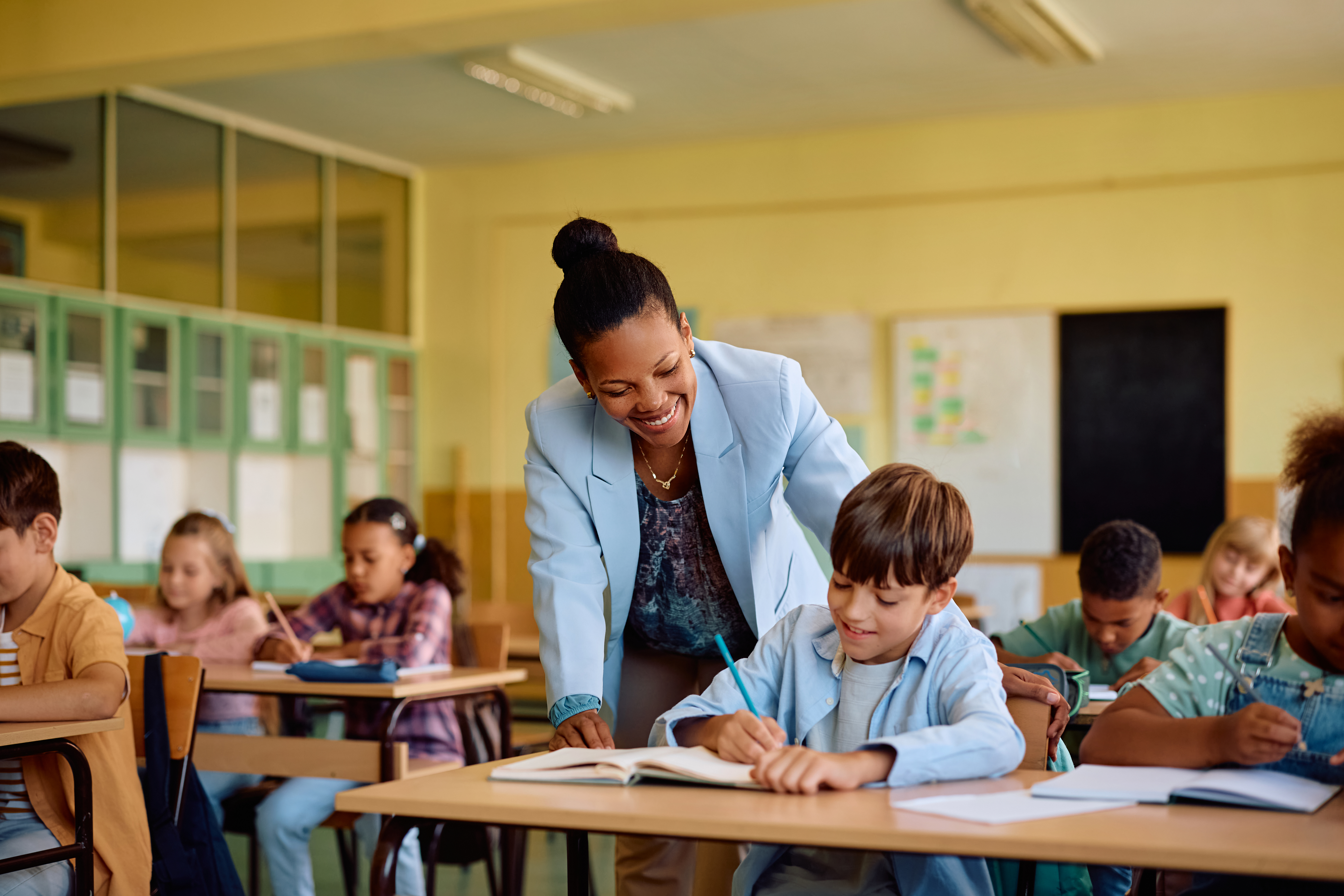 Ambulante onderwijskundige begeleider helpt leerling aan bureau. Ambulante onderwijskundige begeleider helpt leerling aan bureau.