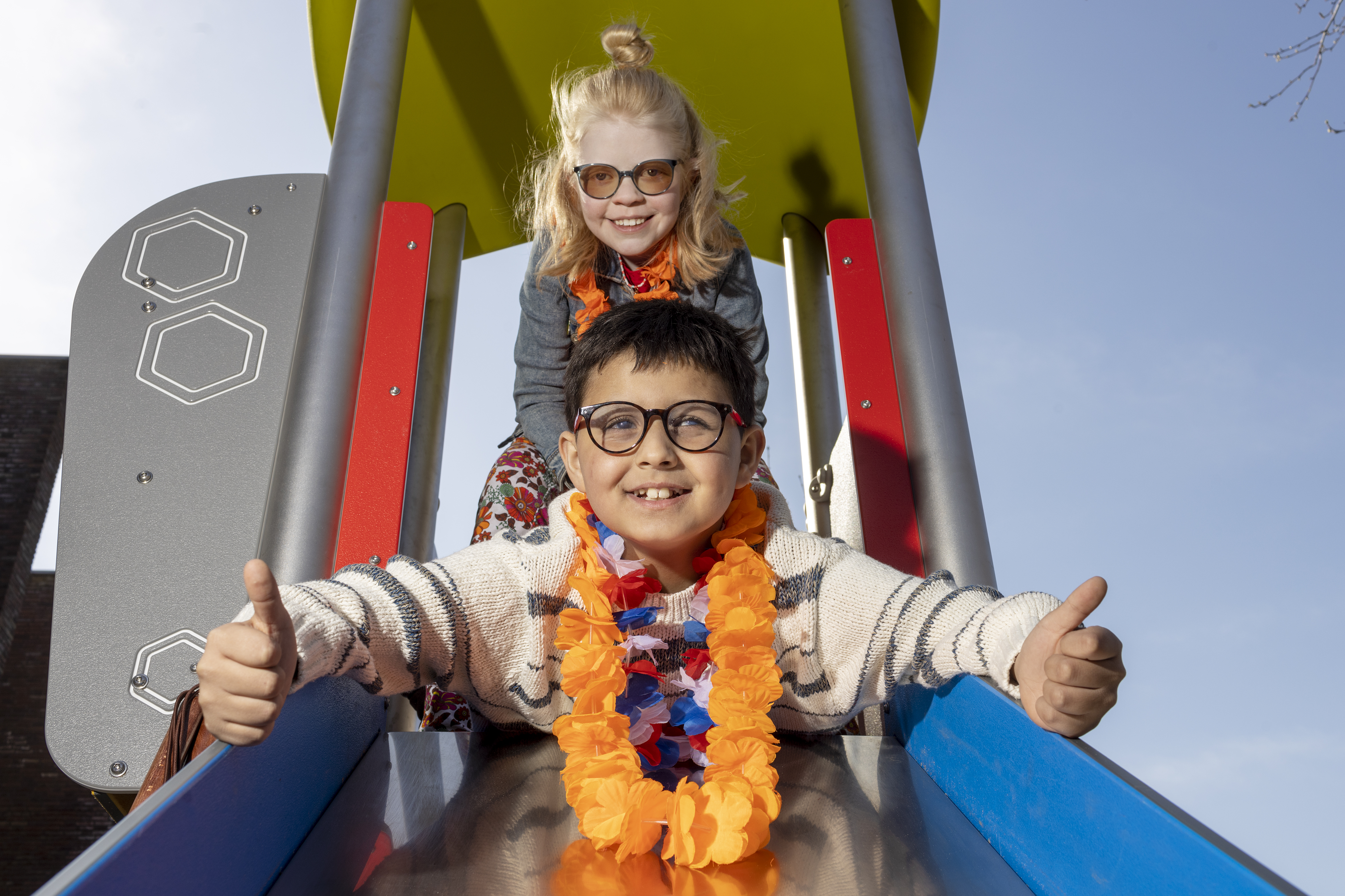 Twee kinderen, een jongen en een meisje, gaan samen van de glijbaan af. De jongen steekt zijn duimen omhoog. Twee kinderen, een jongen en een meisje, gaan samen van de glijbaan af. De jongen steekt zijn duimen omhoog.