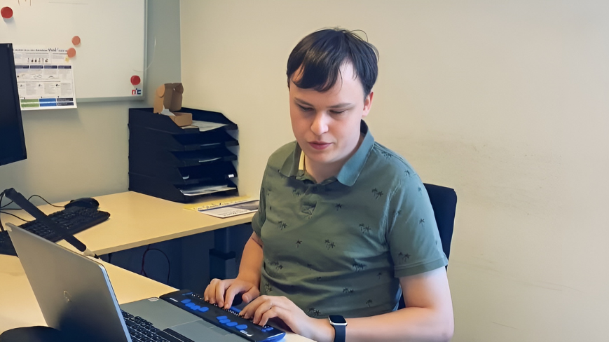 Vince Jansen werkt achter zijn laptop met brailleleesregel
