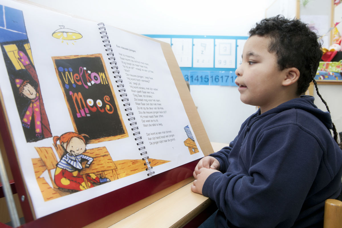 Jongen met een visuele beperking leest op school uit boek met vergroting