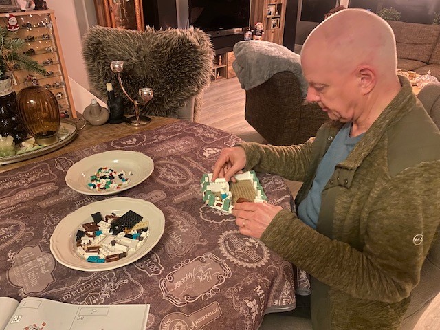 Fred zit aan een ronde tafel. Hij is bezig met een bouwpakket. De onderdelen liggen op twee borden voor hem. Fred zit aan een ronde tafel. Hij is bezig met een bouwpakket. De onderdelen liggen op twee borden voor hem.