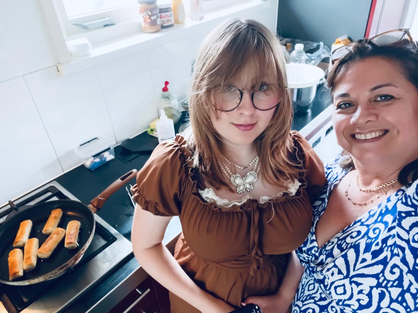 Elsie poseert in de keuken waar zij bij het fornuis staat met daarop een koekenpan met lekkers erin