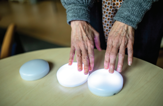 Er liggen drie knoppen op tafel. Twee handen liggen op twee van de knoppen. Er liggen drie knoppen op tafel. Twee handen liggen op twee van de knoppen.