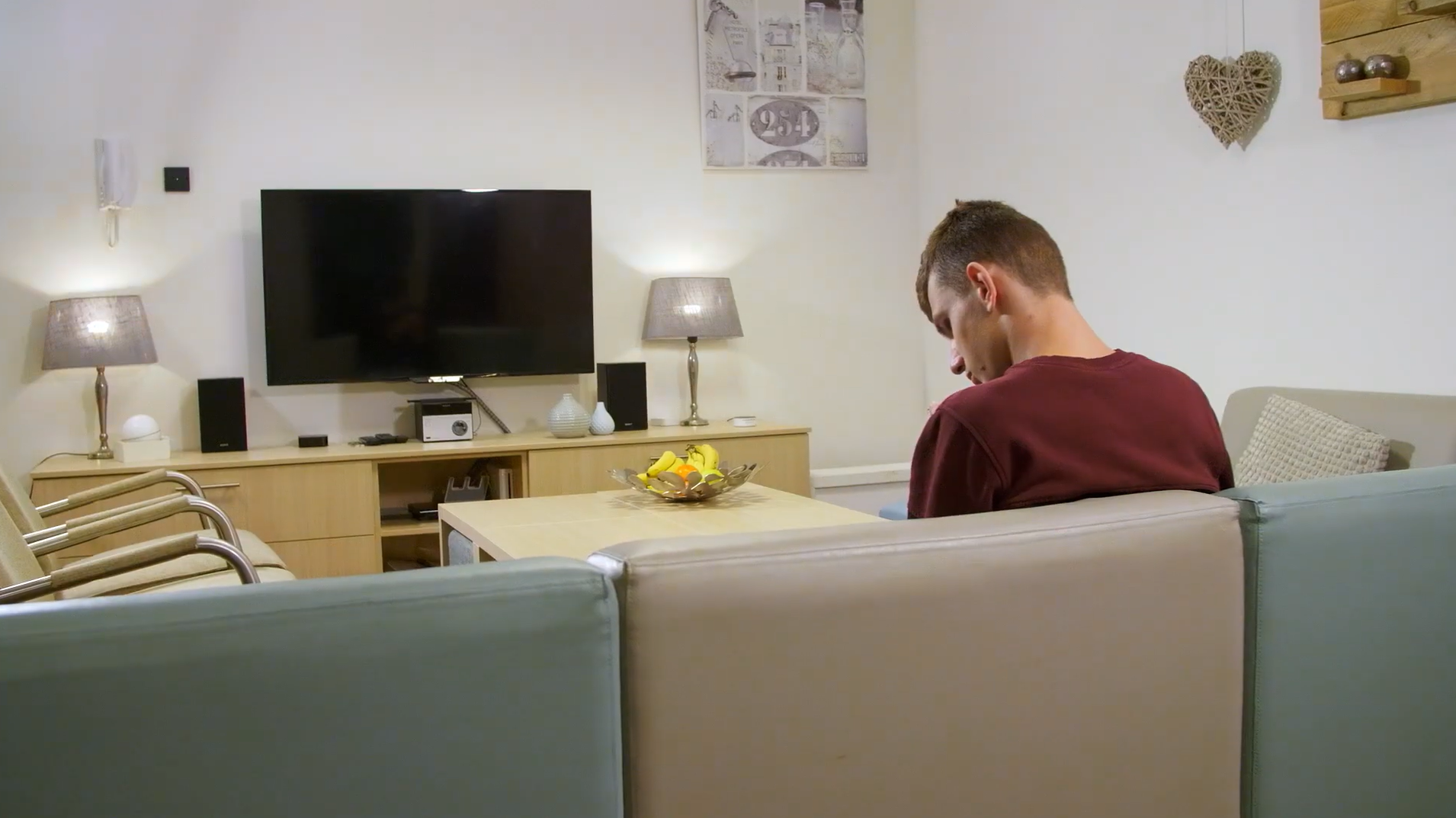Jonge man met een visuele beperking zit in een woonkamer op de bank Jonge man met een visuele beperking zit in een woonkamer op de bank