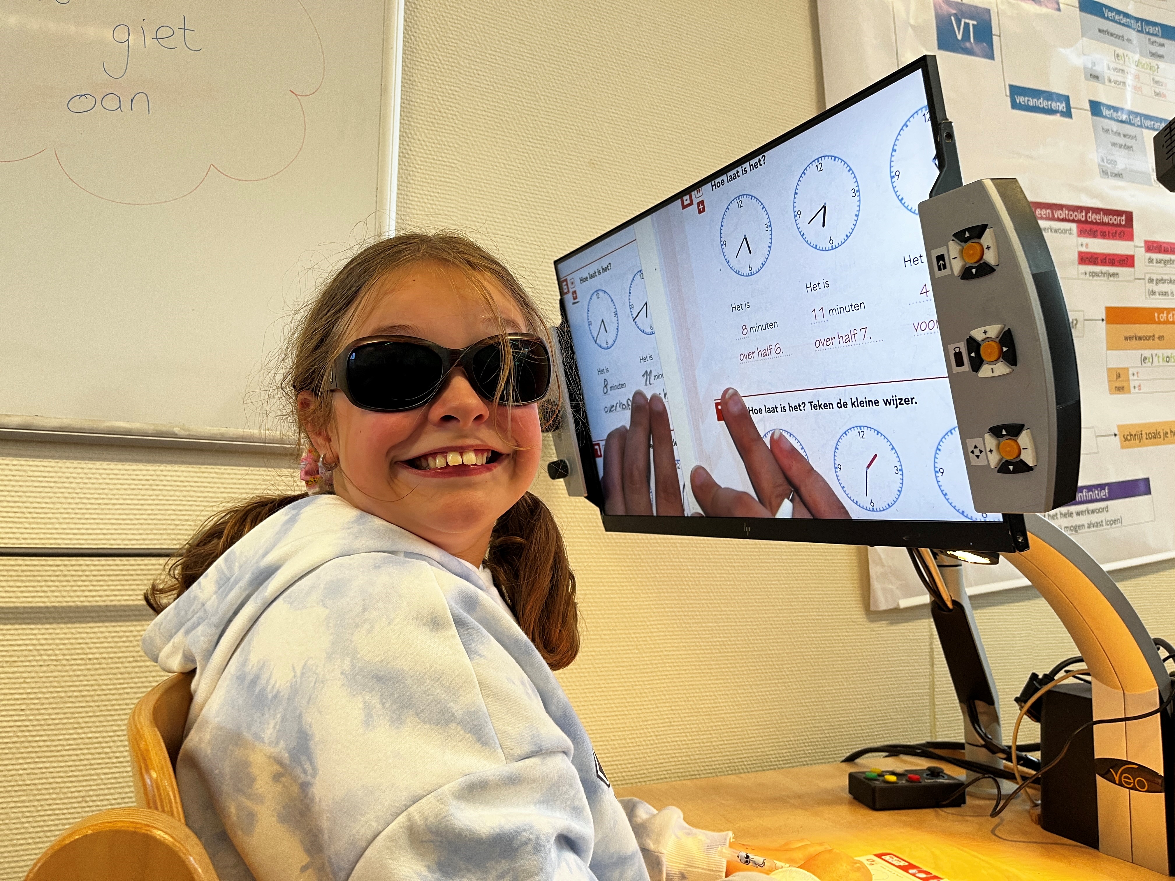 Laura glimlacht naar de camera. Ze draag een zonnebril. Ze zit voor een beeldscherm waarop haar uitvergrootte werkboek te zien is. Laura glimlacht naar de camera. Ze draag een zonnebril. Ze zit voor een beeldscherm waarop haar uitvergrootte werkboek te zien is.