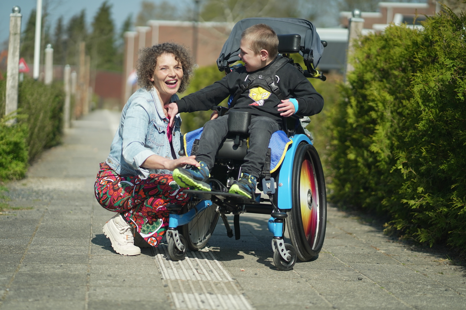 Medewerker en jonge cliënt met een meervoudige beperking in rolstoel poseren samen Medewerker en jonge cliënt met een meervoudige beperking in rolstoel poseren samen