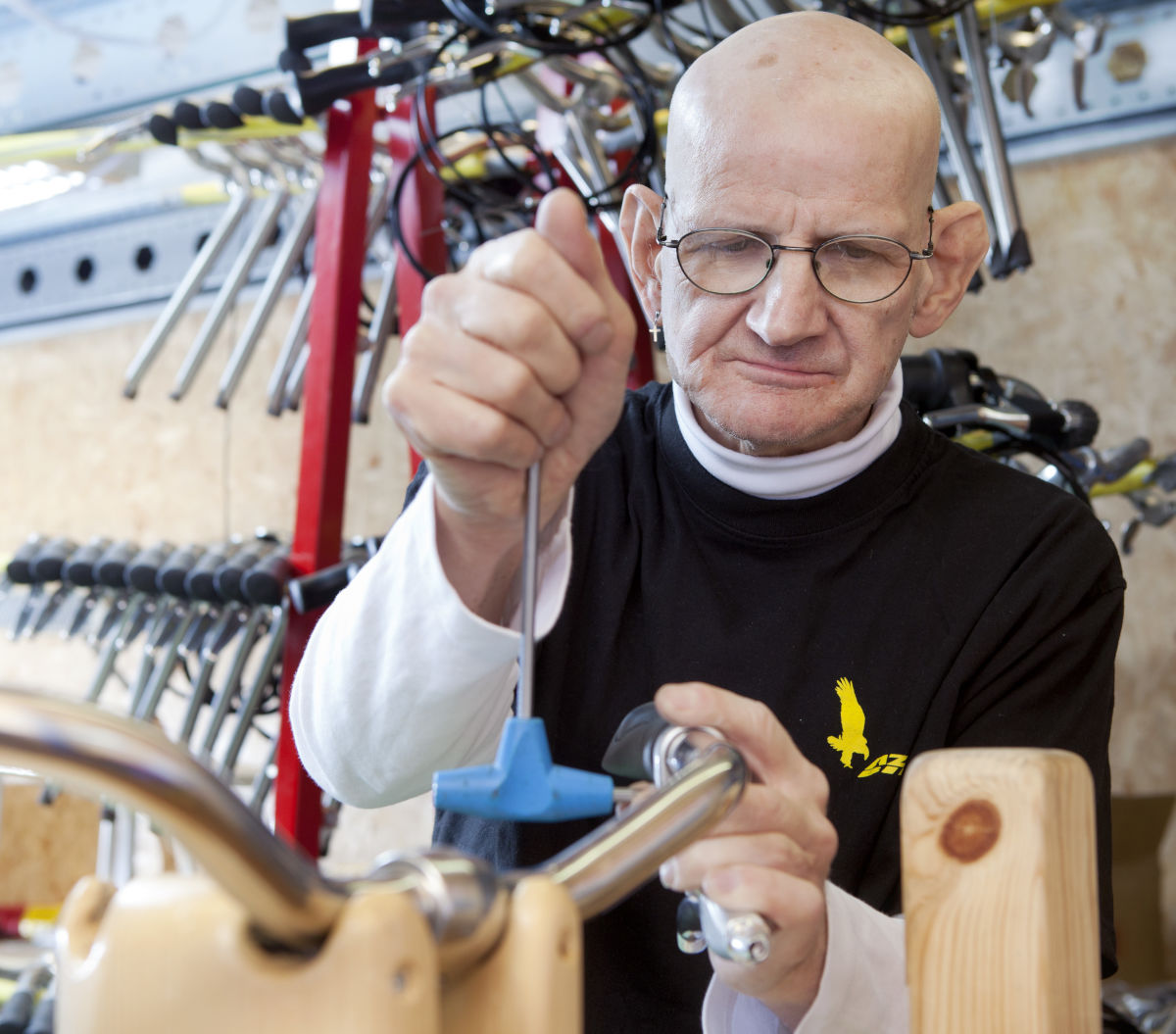 Cliënt van Visio sleutelt aan een stuur van een fiets als dagactiviteit Cliënt van Visio sleutelt aan een stuur van een fiets als dagactiviteit