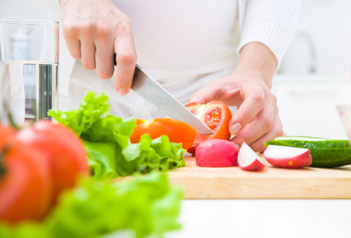 Een close=up van handen die een scherp met vasthouden en groenten snijden. Een close=up van handen die een scherp met vasthouden en groenten snijden.