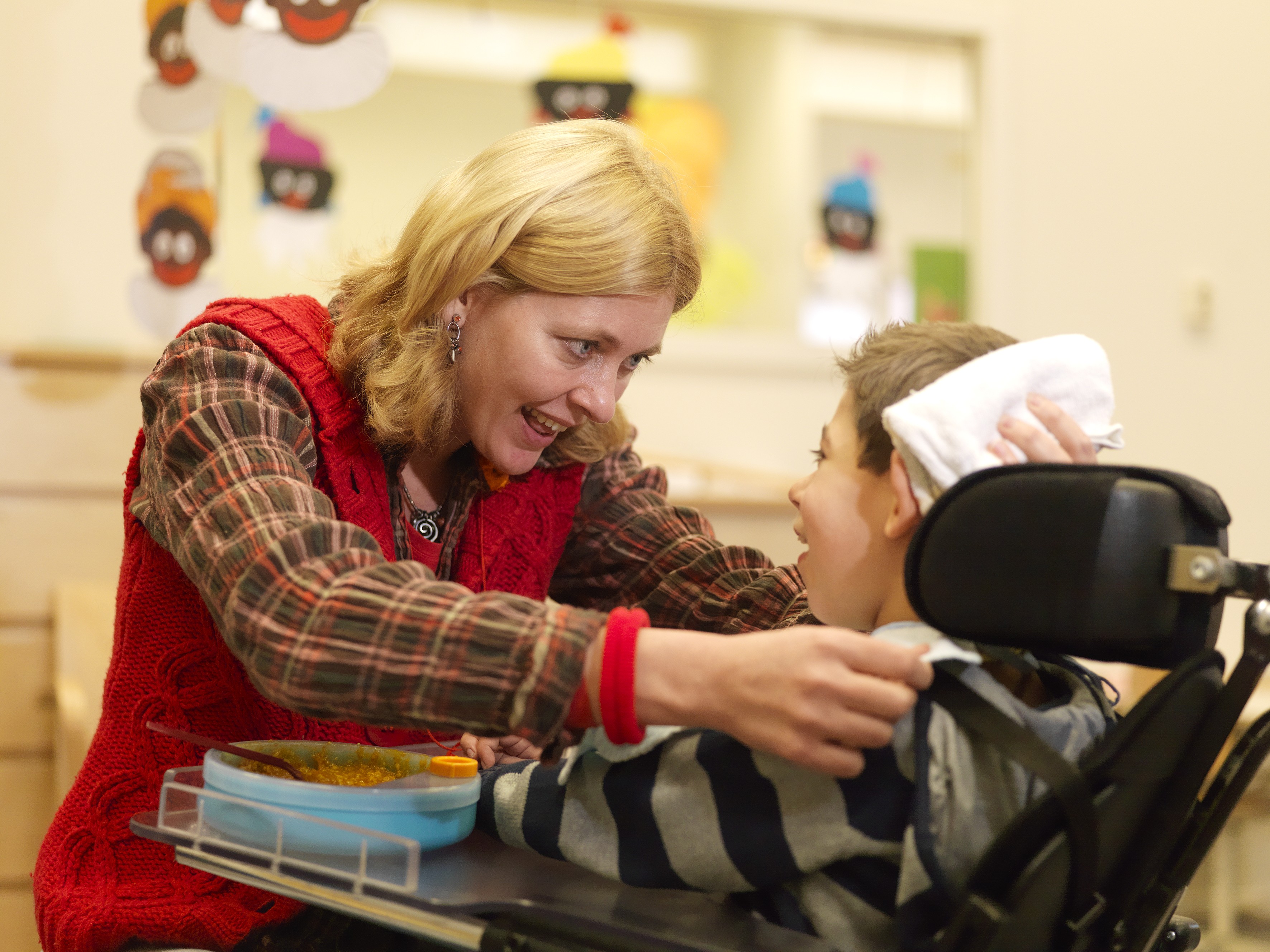 Begeleider heeft oogcontact met kind in rolstoel. Begeleider heeft oogcontact met kind in rolstoel.