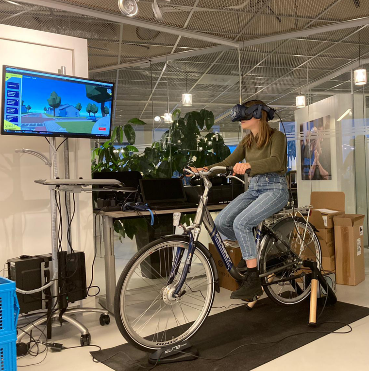 Eva Postuma zit met vr bril op fiets Eva Postuma zit met vr bril op fiets