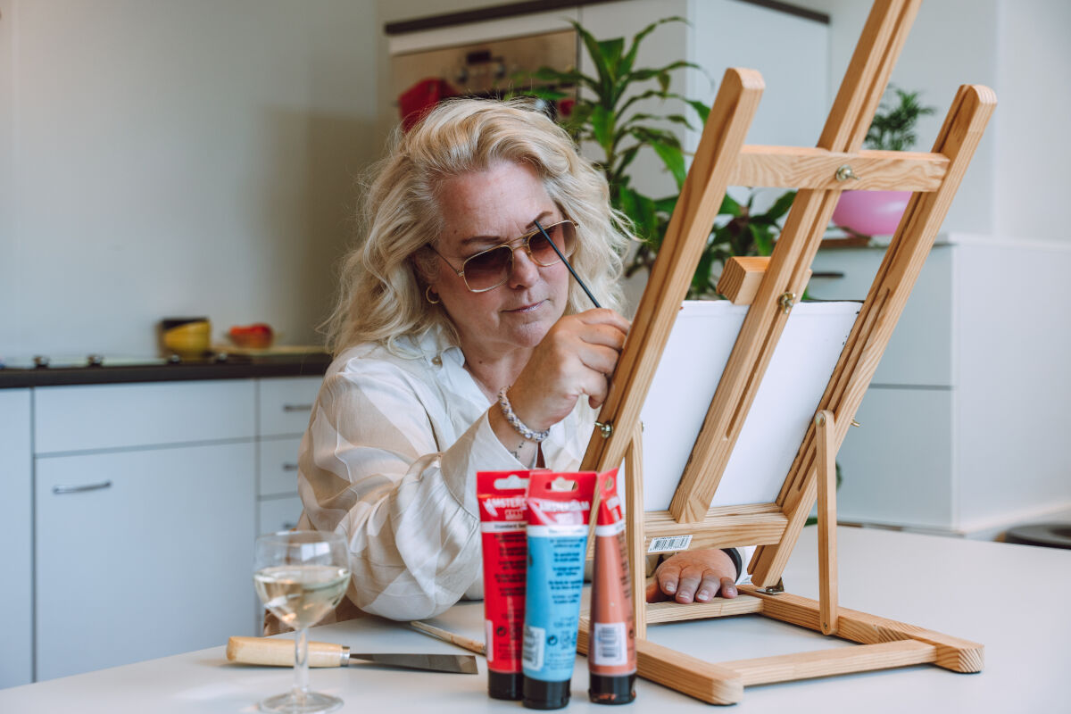 Een blonde vrouw zit aan een tafel. Ze is aan het schilderen. Een blonde vrouw zit aan een tafel. Ze is aan het schilderen.