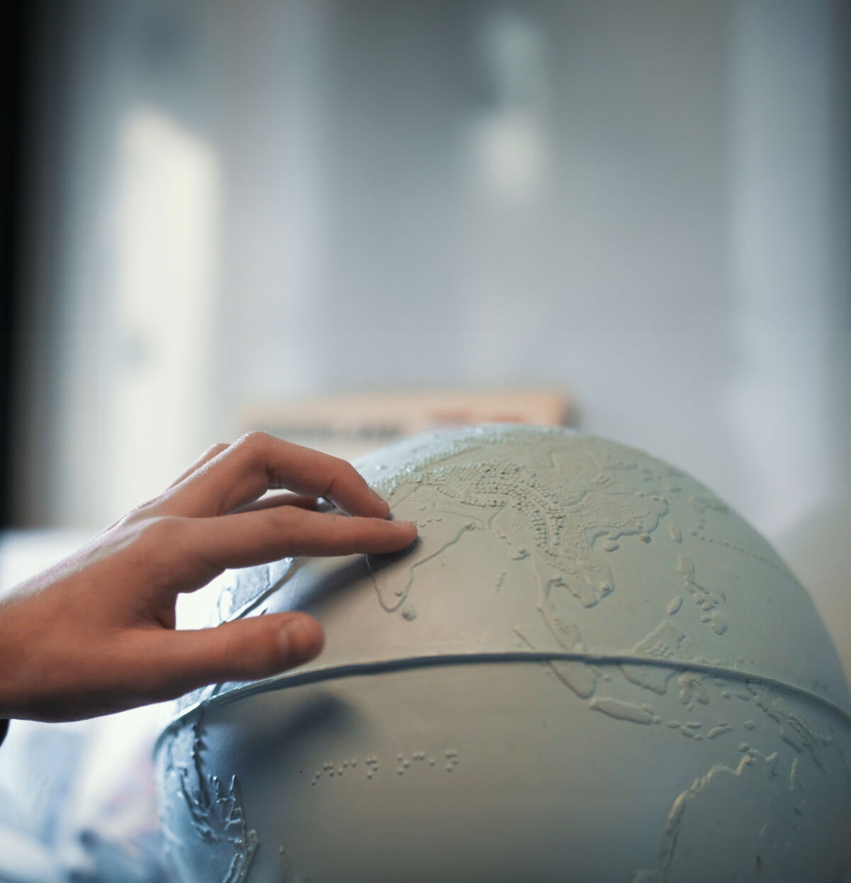 Een hand voelt aan een tactiele wereldbol. Een hand voelt aan een tactiele wereldbol.