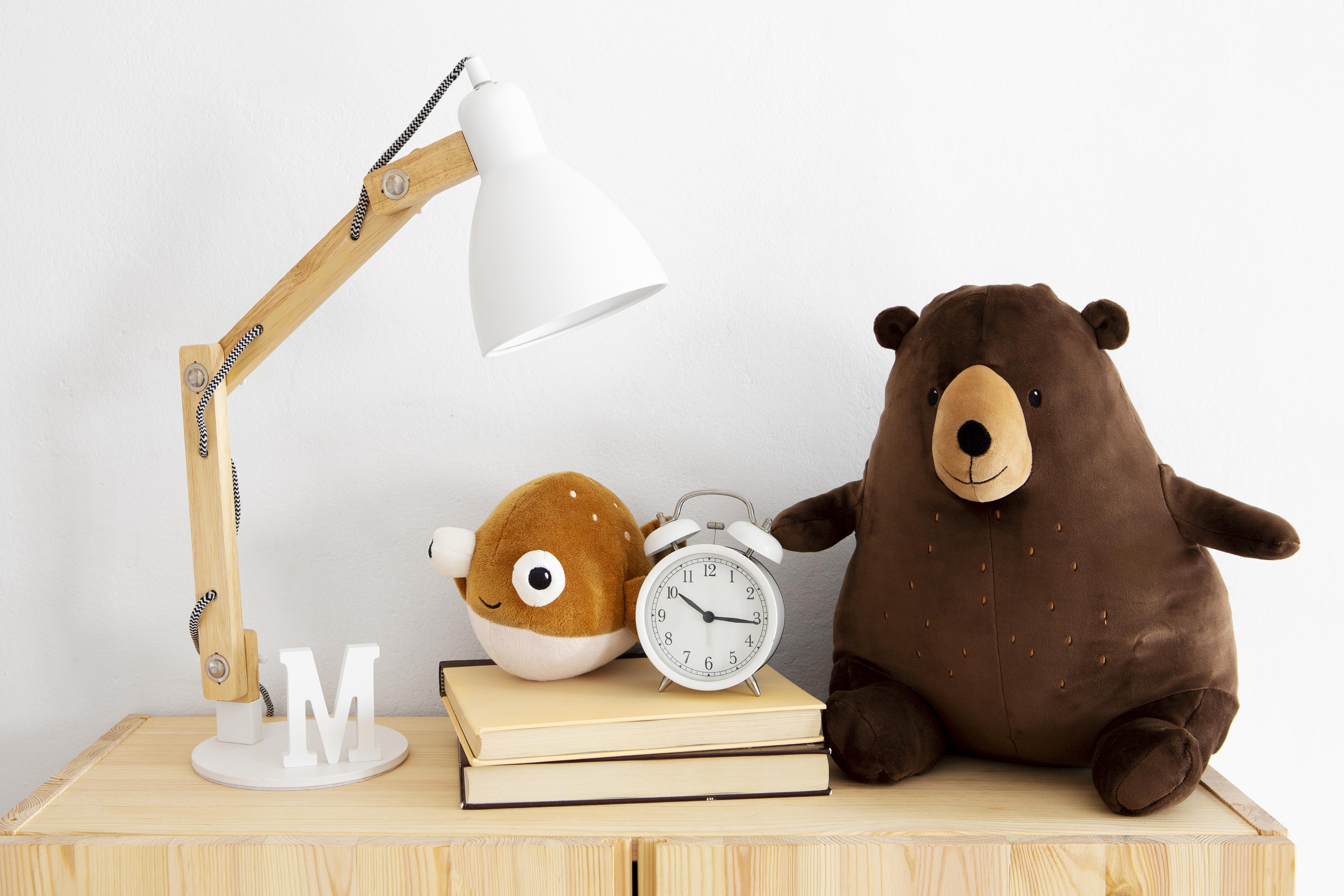 nachtkastje op een kinderslaapkamer met verstelbare lamp, knuffels, wekker en boeken