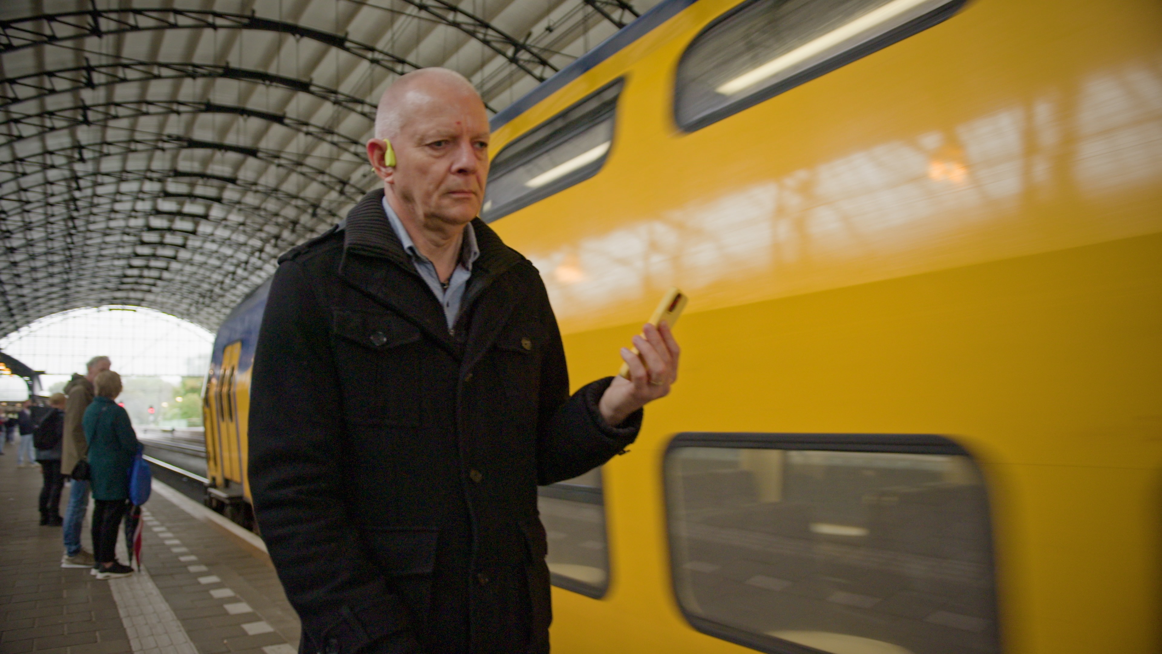 Fred loopt op station. Hij heeft oordopjes in, en heeft zijn telefoon in de hand. Fred loopt op station. Hij heeft oordopjes in, en heeft zijn telefoon in de hand.