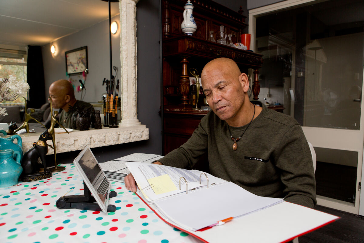 Man met een visuele beperking bladert aan tafel door een map met papieren Man met een visuele beperking bladert aan tafel door een map met papieren