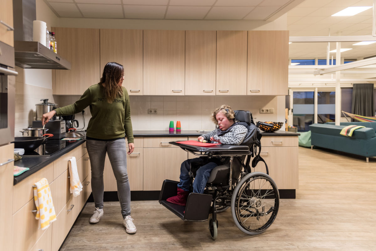 Cliënt in rolstoel en medewerker samen in een keuken van Visio Wonen & Dagbesteding Meppel Cliënt in rolstoel en medewerker samen in een keuken van Visio Wonen & Dagbesteding Meppel