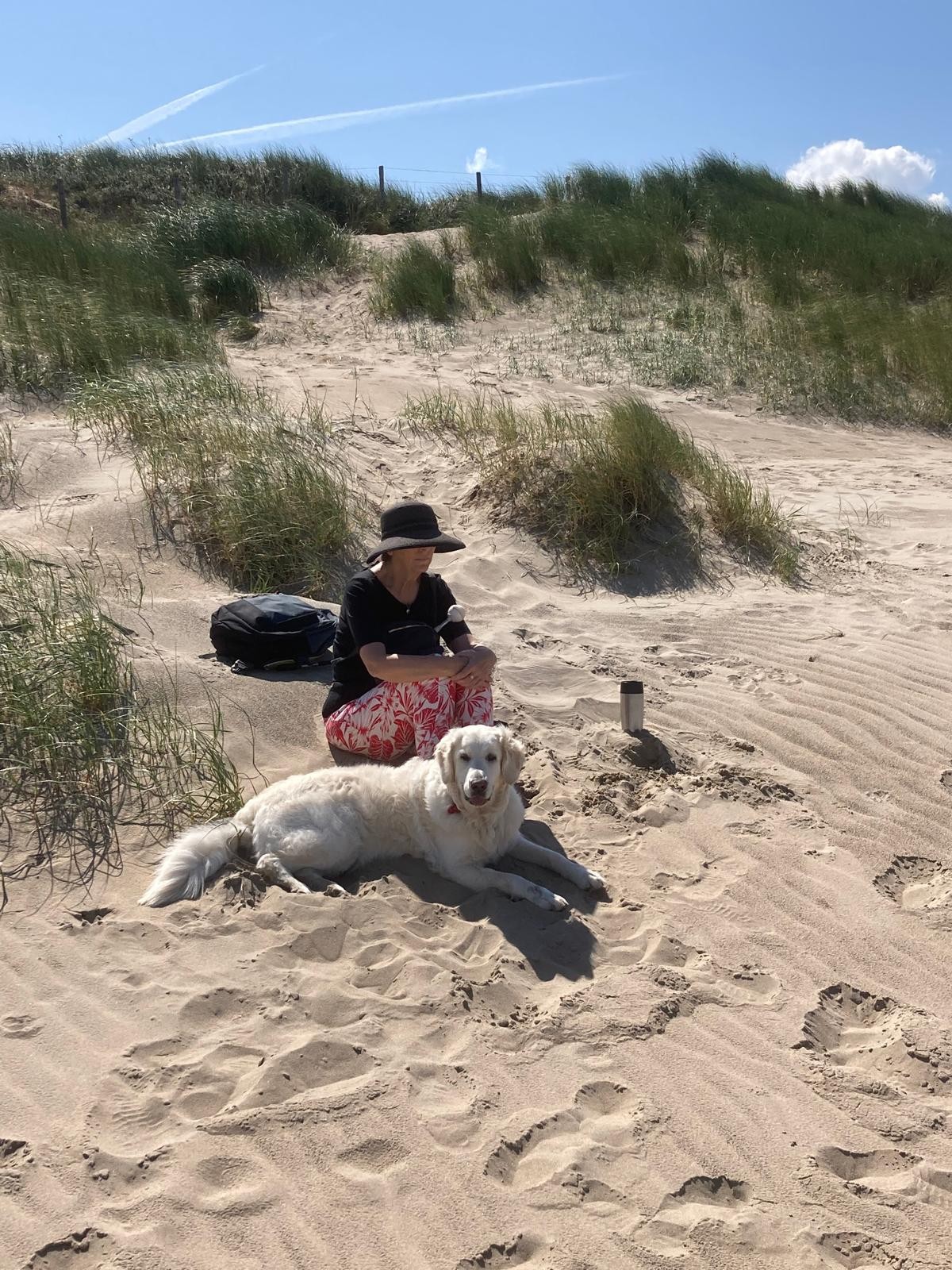 Sabrina zit op het strand met haar geleidenhond Sabrina zit op het strand met haar geleidenhond
