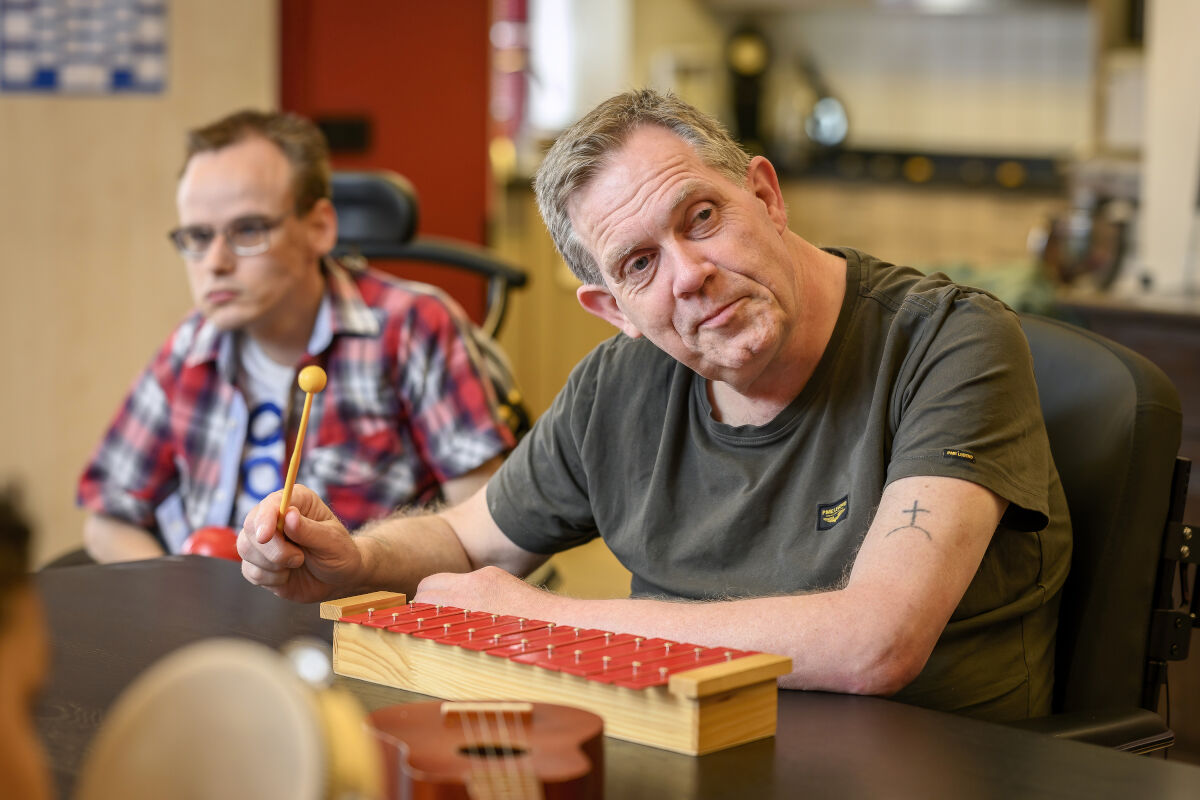 Cliënt met een visuele en verstandelijke beperking speelt op een xylofoon Cliënt met een visuele en verstandelijke beperking speelt op een xylofoon