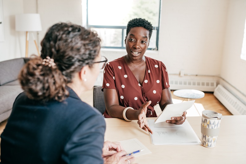 Twee dames met elkaar in gesprek een een bureau