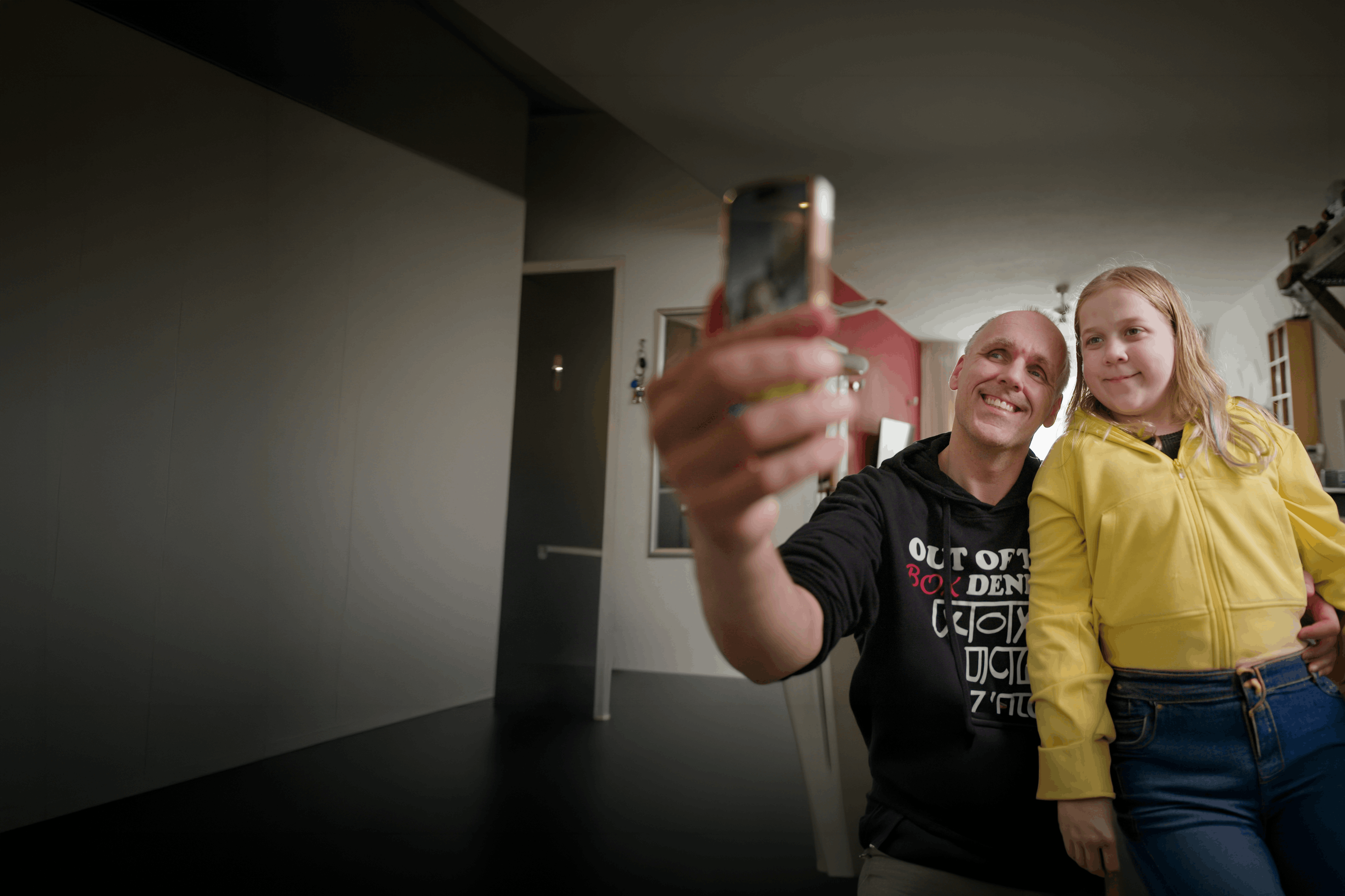 Een slechtziende man van middelbare leeftijd en zijn dochter van ongeveer 13 jaar maken samen een selfie. Ze kijken allebei lachend naar de camera van de telefoon. Een slechtziende man van middelbare leeftijd en zijn dochter van ongeveer 13 jaar maken samen een selfie. Ze kijken allebei lachend naar de camera van de telefoon.